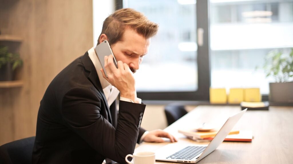 Empresário ao telefone em frente ao notebook planejando o investimento em anúncios